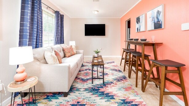 Un salon avec un canapé, une table basse et un téléviseur fixé au mur.