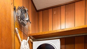 Un espace réduit dédié à la buanderie, comprenant un lave-linge, un sèche-linge et un aspirateur.