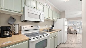 Una cucina con elettrodomestici bianchi, una macchina da caffè e un cartello con la scritta 'BEACH HOUSE'.