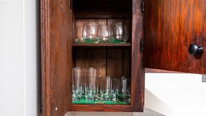 Eine Holzschrank mit mehreren Regalen, auf denen klares Glasgeschirr steht.