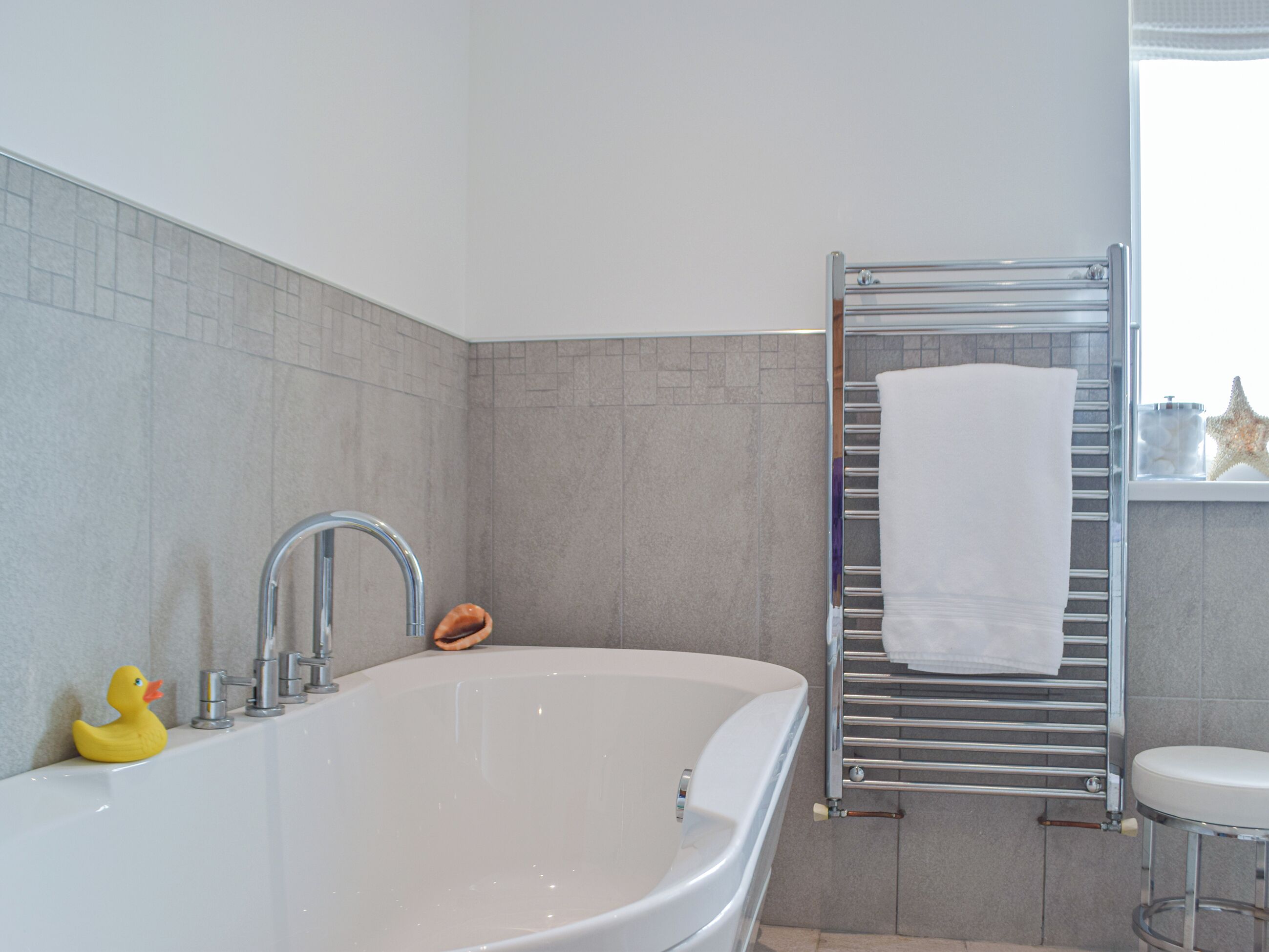 Une salle de bain moderne avec une baignoire sur pieds, un robinet chromé, un porte-serviettes et une décoration en forme d’étoile de mer.