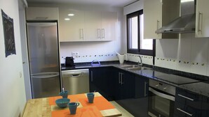 Une cuisine de taille réduite équipée d’un réfrigérateur, d’un lave-vaisselle, d’une cuisinière et d’un évier.