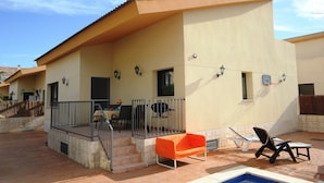 Un bâtiment moderne doté d’un patio couvert, d’un espace salon extérieur et d’une piscine.