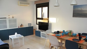 Un espace repas moderne comprenant un téléviseur, une table à manger, des chaises et une fenêtre avec des stores.