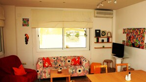 Una habitación con un sofá, una silla roja, una mesa de madera y un televisor.