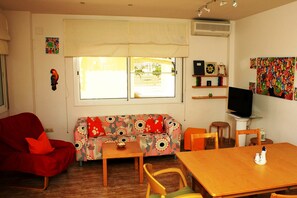 A room with a sofa, a red chair, a wooden table, and a television.