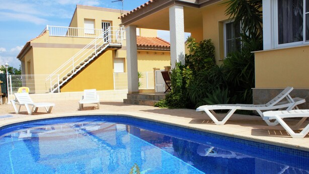 Una piscina con un mosaico de estrellas, sillas de descanso blancas y una escalera que lleva a un balcón.
