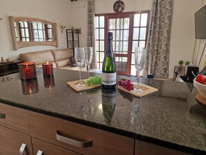 En køkkenø med en vinflaske, to glas og en skål med druer.