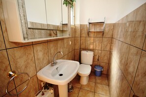 Een badkamer met een wastafel, toilet en spiegel.