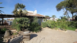 Un cortile con pavimento in pietra, palme e una panchina di legno.