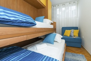 Una habitación con una cama nido, un sofá y una ventana con cortinas.