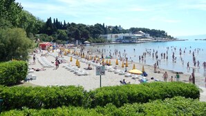 A beach with rows of sun loungers and umbrellas, a sign prohibiting dogs, and a building in the background. - Apt. Near Center With Balcony With the sea View (Split)