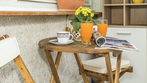 A wooden table with a white mug, a glass of orange juice, a vase with yellow flowers, and a magazine. - Apt. Near Center With Balcony With the sea View (Split)