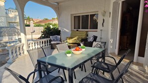 Eine Terrasse im Freien mit Tisch, Stühlen und einer Obstschale.
