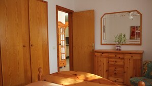 Ein Schlafzimmer mit einem Holzbett, einem Schminktisch, einem Spiegel und einem Sessel.