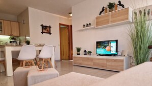 Un soggiorno moderno con televisione, mobili bianchi e un mobile in legno.