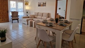 Un soggiorno moderno con divano, tavolo da pranzo, sedie e angolo cottura con frigorifero.