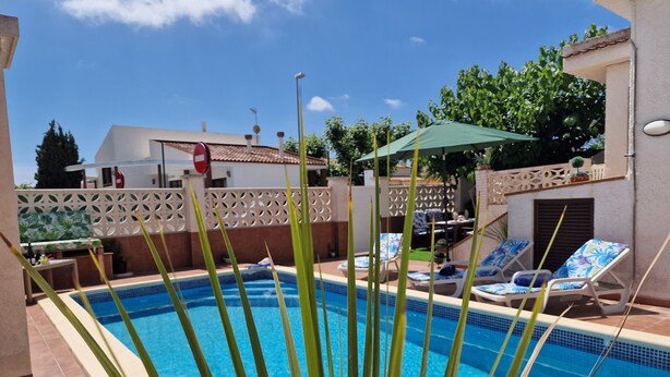 Una piscina con sillones de descanso y un área de terraza.