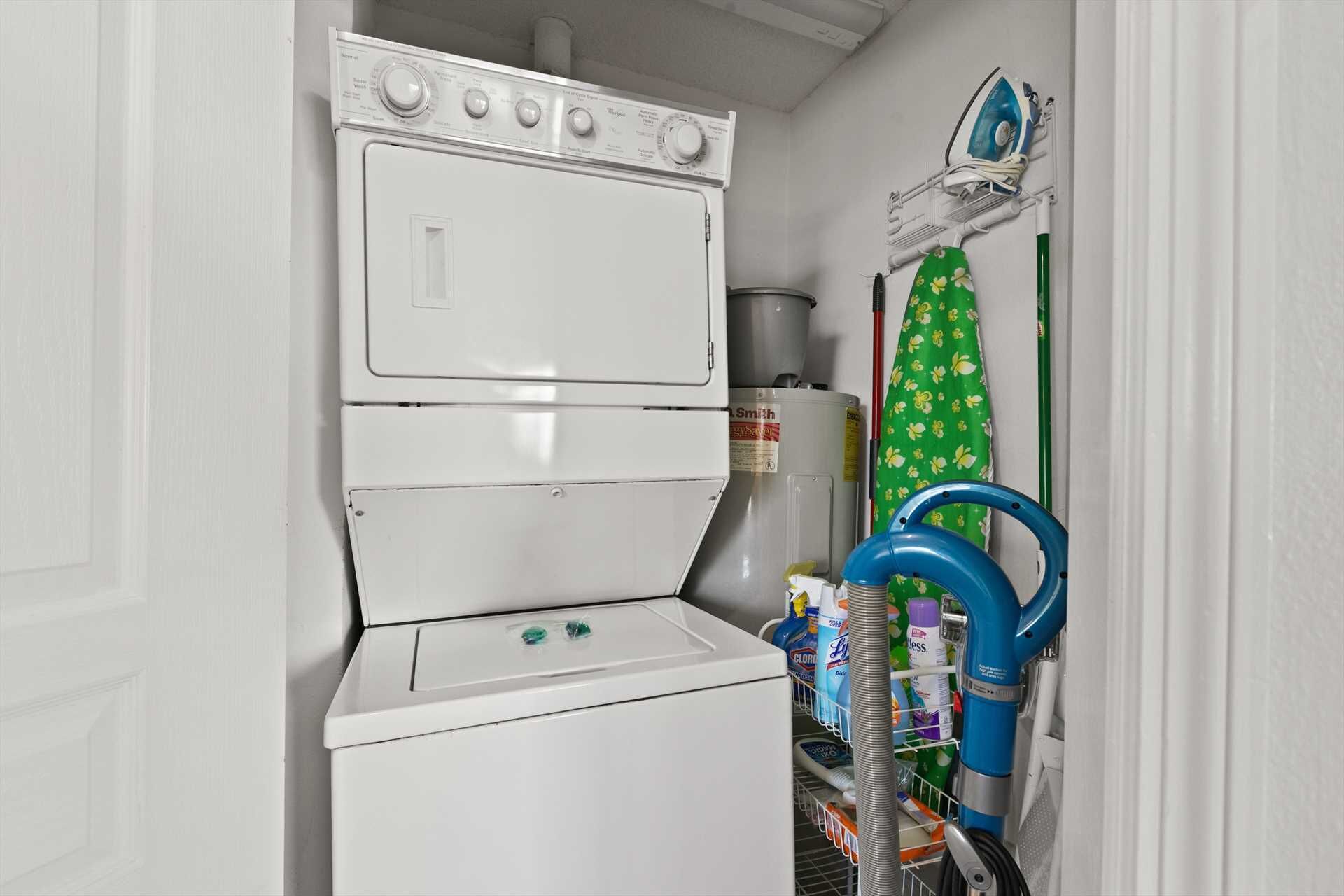 A laundry area with a washer and dryer, a water heater, and a steam iron on a rack.