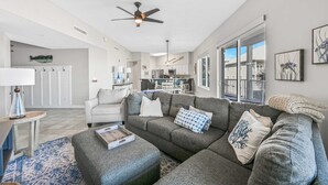A modern living room with a grey sectional sofa, a small table with a tray, and a ceiling fan. - Crystal View 203 3 bedroom/  3 bath unit Beach service great view SO MUCH SPACE (Miramar Beach)
