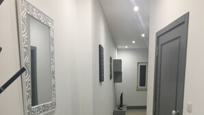 A hallway with a mirror, a door, and a small cabinet.
