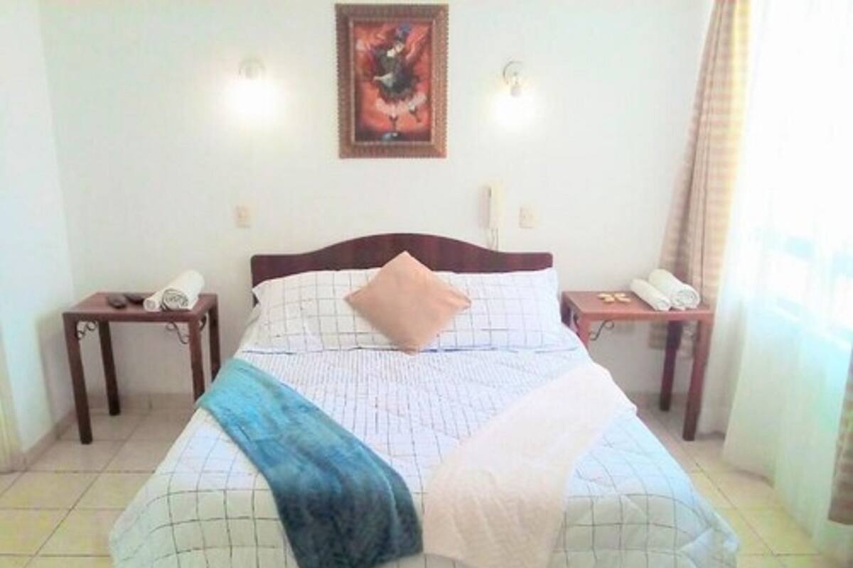 A neatly made bed with a blue throw blanket, a wooden headboard, and two bedside tables with lamps.