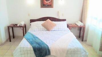 A neatly made bed with a blue throw blanket, a wooden headboard, and two bedside tables with lamps.