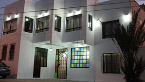 Un bâtiment moderne à deux étages, doté de nombreuses fenêtres et d’une entrée centrale ornée d’une porte décorative.