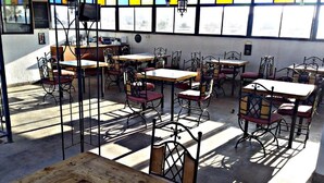 Un café doté de nombreuses tables et chaises, disposées dans un espace intérieur vaste et lumineux.