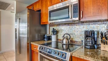 A modern kitchen with stainless steel appliances, wooden cabinets, and a tiled backsplash.