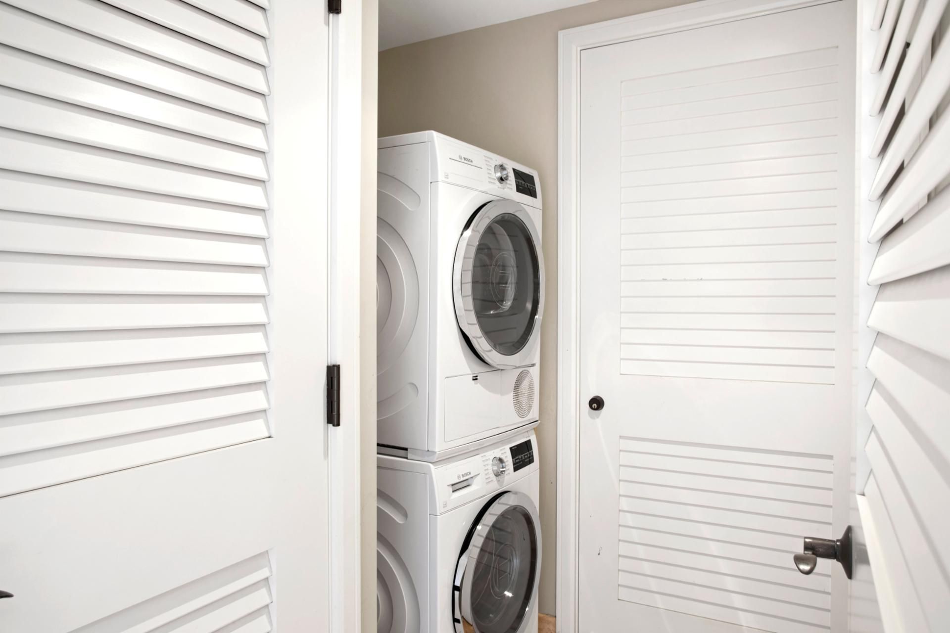 A laundry room with two stacked front-loading washing machines and a closed door.