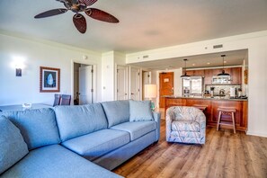 Ein Wohnzimmer mit einer Couch, einem gemusterten Sessel und einem Deckenventilator.