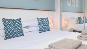 A neatly made bed with patterned pillows, a bedside lamp, and a folded towel on the side. - The Captains Hideaway (Sageston, near Tenby)