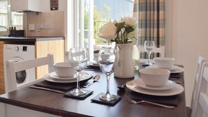 A dining table set with white plates, bowls, cutlery, and a vase with flowers. - The Captains Hideaway (Sageston, near Tenby)