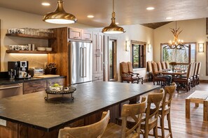 A spacious kitchen with a large island, wooden cabinets, and a dining area with a chandelier.