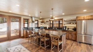 A spacious kitchen with a central island, wooden cabinets, and stainless steel appliances.