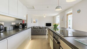 A modern kitchen with a central island, built-in appliances, and a seating area with a sofa.