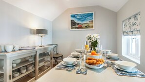 Una cucina moderna con un tavolo da pranzo per quattro persone, un armadietto con stoviglie, un quadro appeso e una finestra con vista.