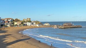 Una cittadina costiera con edifici lungo la spiaggia, un molo e un faro.