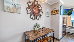 Un coin repas avec une table en bois, deux verres à vin et un élément décoratif mural.