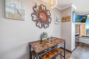 Ein Essbereich mit einem Holztisch, zwei Weingläsern und einem dekorativen Wandbild.