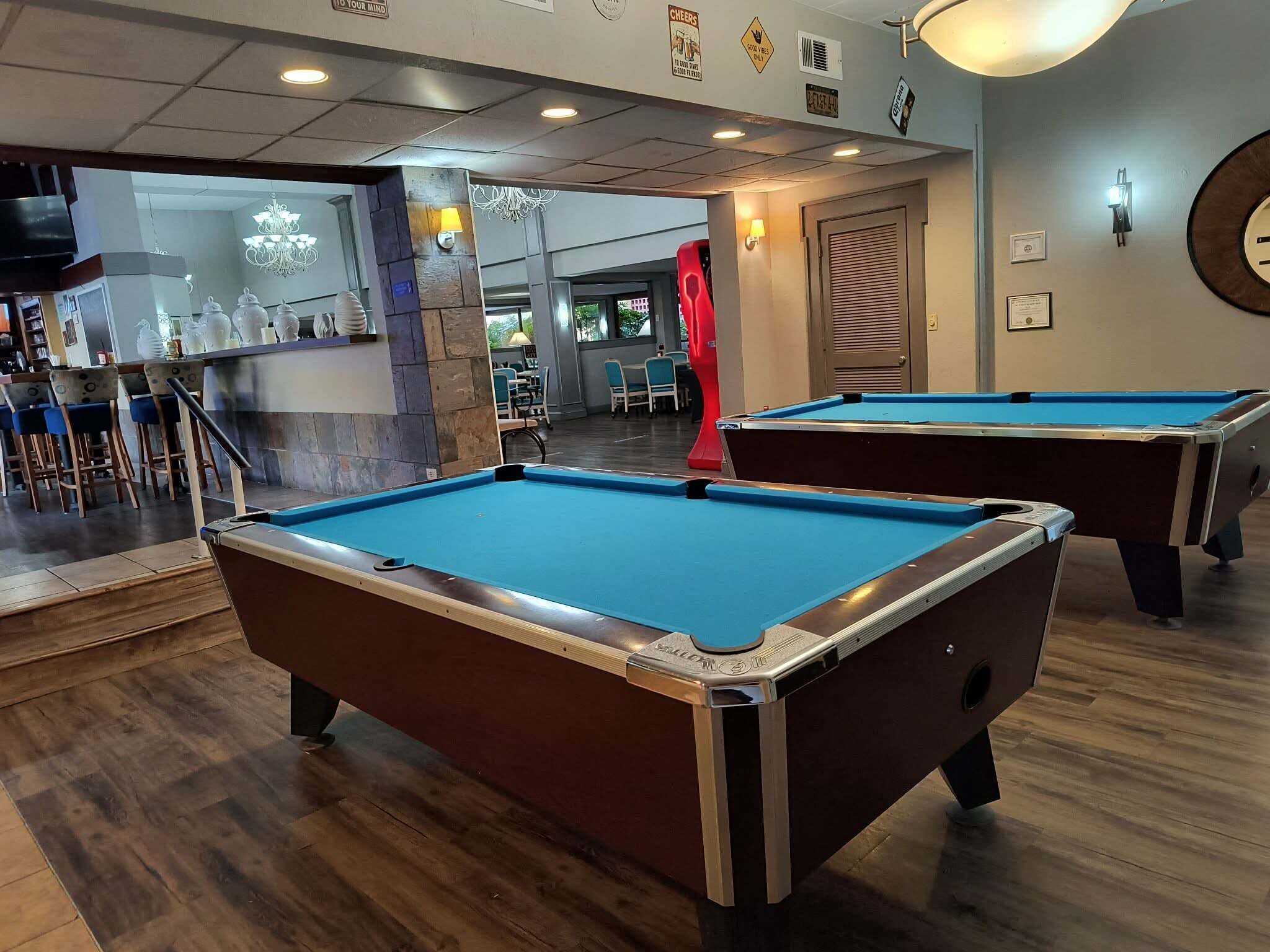 Ein Billardtisch mit Holzboden und einer Bar im Hintergrund.