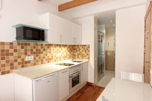 Een moderne keuken met witte kasten, een magnetron, een spoelbak en een vaatwasser.