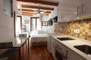 Une cuisine compacte avec un coin repas, un lit et un ventilateur de plafond.