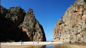 A beach with rocky cliffs and clear shallow water. - La lonja -- old town Palma (Palma de Mallorca)