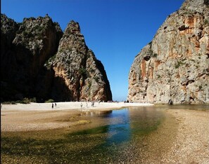 Une plage bordée de falaises rocheuses et aux eaux claires et peu profondes.