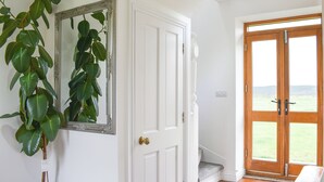 A hallway with a white door, a mirror, and a potted plant.