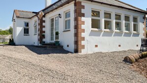 A two-story house with a white exterior, a brown brick accent wall, and a gravel driveway.