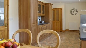 A kitchen with wooden cabinets, a dining table with chairs, and a fruit bowl.