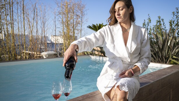 Una persona sirve vino en copas junto a una piscina.